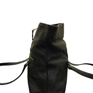 May include: A black leather tote bag with two top handles and a zip closure.