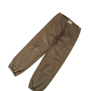 May include: A pair of brown cotton pants with a drawstring waist and elastic cuffs. The pants have a relaxed fit and are made of a lightweight fabric.