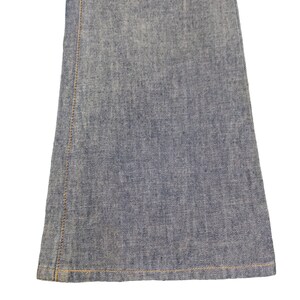 May include: Close-up of the bottom hem of a pair of blue denim jeans. The jeans have a straight leg and a raw hem.