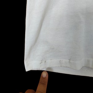 May include: White t-shirt with a slight discolouration on the bottom hem.