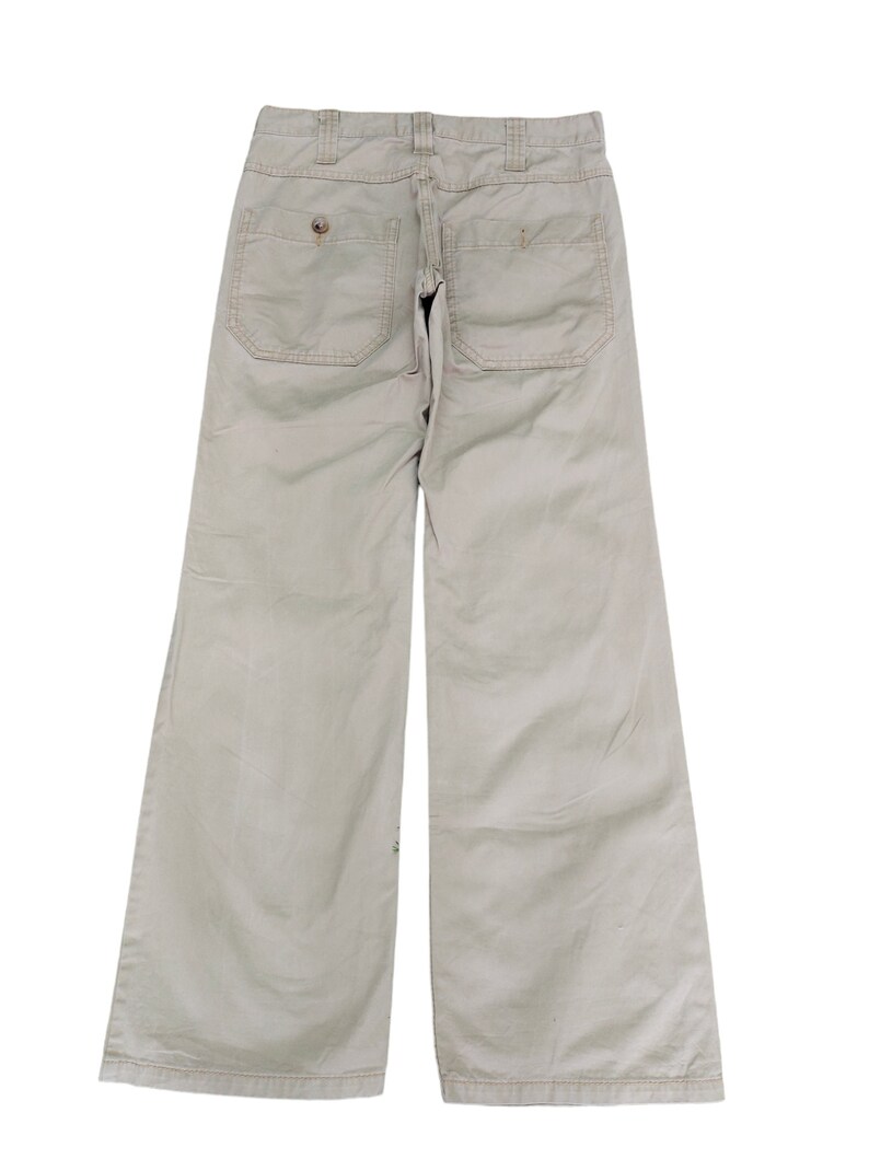 Puede incluir: Un pantal&oacute;n de pierna ancha de color beige claro con dos bolsillos grandes en la parte posterior.