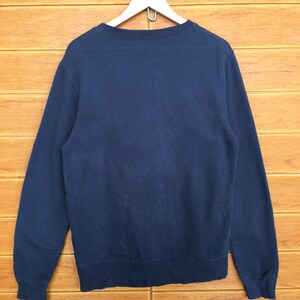 May include: A dark blue long-sleeved sweatshirt hanging on a wooden hanger.