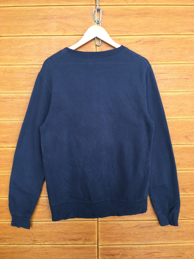May include: A dark blue long-sleeved sweatshirt hanging on a wooden hanger.