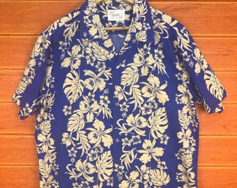 May include: A blue short-sleeved button-down shirt with a white floral print. The shirt has a collar and a pocket on the left side. The shirt is made of a lightweight fabric and is perfect for warm weather.