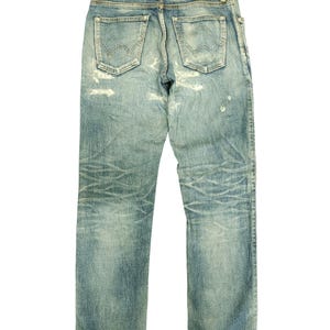 May include: Light blue denim jeans with a distressed look, featuring faded areas and worn details. The back view shows the pockets, belt loops, and a small "EDWIN" label. The jeans have a classic, straight-leg fit.