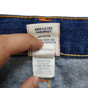 K&ouml;nnte beinhalten: Ein blaues Jeans-Etikett mit wei&szlig;em Text. Das Etikett lautet "RN#112790 CA#30427 100% COTTON NE WASH COLD INSIDE OUT 4-059326 CUT#602134 STYLE# 04-803 PO#59487 100% COTTON 100%COTON MADE IN USA FABRIQUE AU EUA CA#30427"