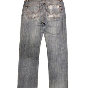 May include: Faded blue denim jeans with a distressed look. Features include two back pockets with a distinctive stitched design, a leather patch with the brand name "EDWIN", and a red tag. The jeans have a straight leg cut and frayed hems.