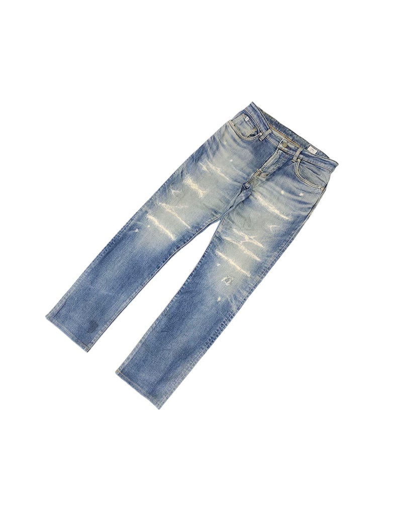 May include: Light blue denim jeans with distressed detailing. The jeans have a classic five-pocket design, a button and zipper closure, and a straight leg fit. The denim has a faded wash with intentional rips and abrasions.