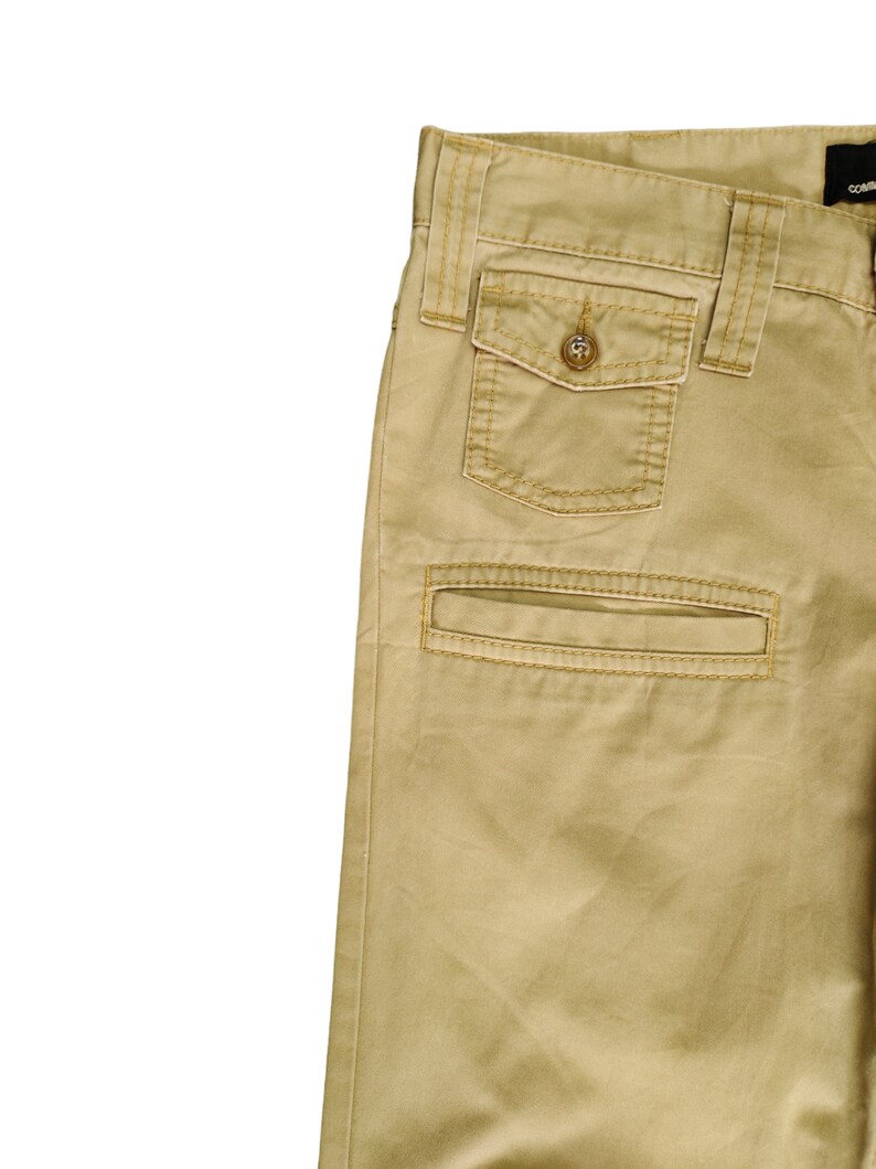 Puede incluir: Un pantal&oacute;n cargo color caqui con un bolsillo grande en el lado derecho. El bolsillo tiene un cierre de bot&oacute;n y est&aacute; acentuado con costuras.