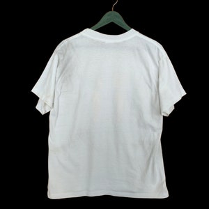 May include: A white t-shirt hanging on a green hanger against a black background.