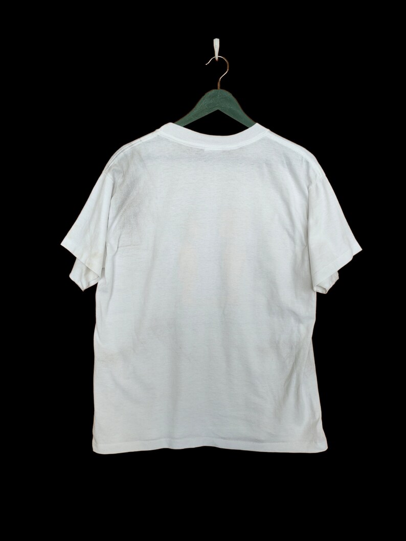 May include: A white t-shirt hanging on a green hanger against a black background.