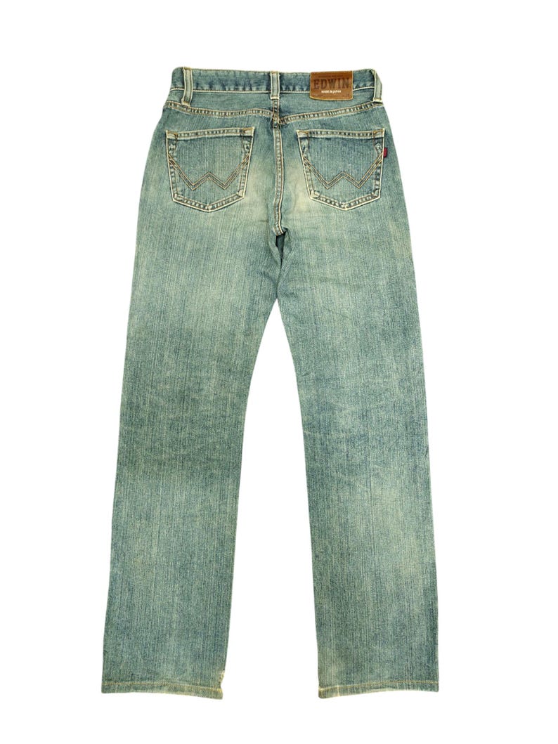 May include: Light blue denim jeans with a faded wash. The jeans feature classic five-pocket styling, a brown leather patch with the brand name, and decorative stitching on the back pockets. The jeans are a straight-leg style.