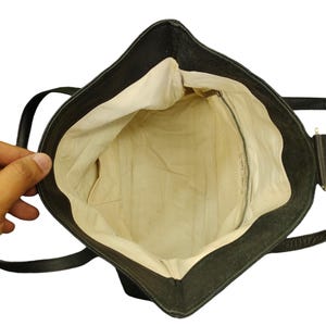 May include: A black leather tote bag with a cream coloured lining. The bag has a zipped pocket on the inside and two straps.