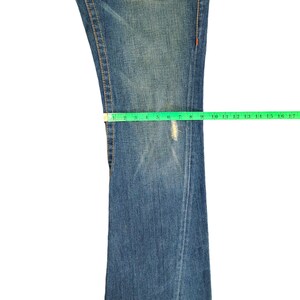 May include: A pair of blue denim jeans with a light wash. The jeans have a straight leg and are measured with a tape measure.