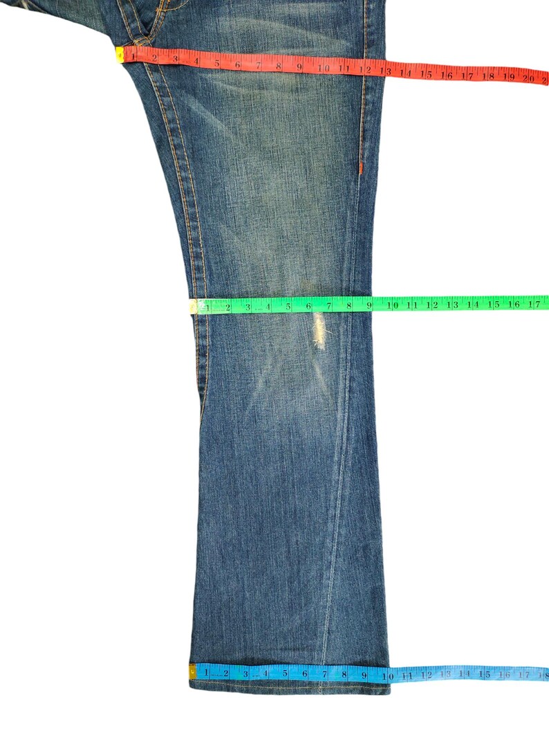 May include: A pair of blue denim jeans with a light wash. The jeans have a straight leg and are measured with a tape measure.
