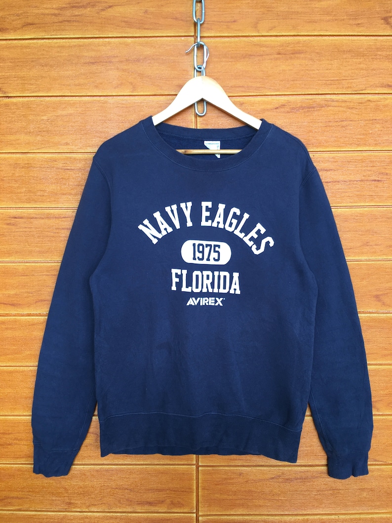 May include: Navy blue sweatshirt with white text that reads "Navy Eagles 1975 Florida Avirex".