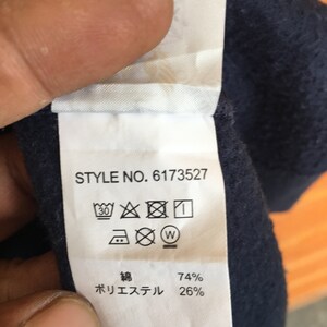May include: A white care label with black text and symbols. The text reads "STYLE NO. 6173527" and "74% Polyester 26%". The symbols include a washing machine icon with a 30 degree symbol, an iron icon with a dot, a dry clean icon with a circle and a cross, and a tumble dry icon with a circle and a cross.