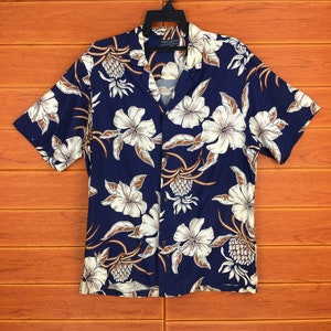 May include: A blue short-sleeved button-down shirt with a white and brown floral print. The shirt has a collar and a button closure.