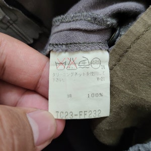 May include: A white care label with instructions for washing and drying the garment. The label also includes the fabric content, which is 100% cotton. The label has the text "TC23-FF232" printed on it.