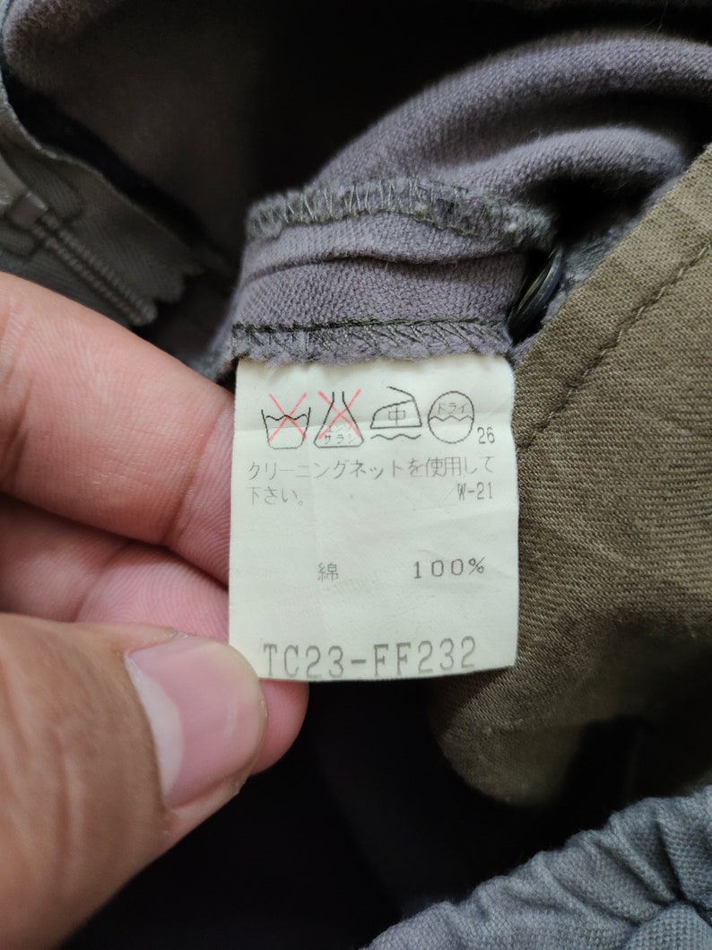 May include: A white care label with instructions for washing and drying the garment. The label also includes the fabric content, which is 100% cotton. The label has the text "TC23-FF232" printed on it.