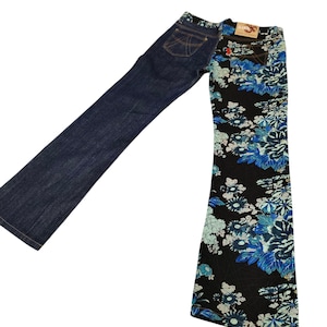 May include: A pair of denim jeans with a unique split design. One leg is solid dark blue, while the other features a black floral pattern with blue and white flowers. The jeans have a classic five-pocket design and a red tag.