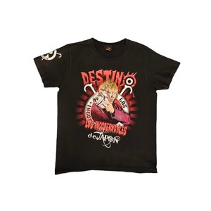 Peut inclure: T-shirt noir avec un imprimé graphique rouge et blanc d'un homme tenant un crâne. Le graphique comprend le texte "DESTINO", "LOS INGOBERNABLES" et "de JAPON".