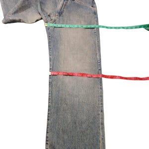 May include: Light blue denim jeans with a classic five-pocket design. A green measuring tape shows a waist measurement of approximately 22 inches. A red measuring tape shows an inseam measurement of approximately 17 inches. A blue measuring tape shows a leg opening of approximately 9 inches.