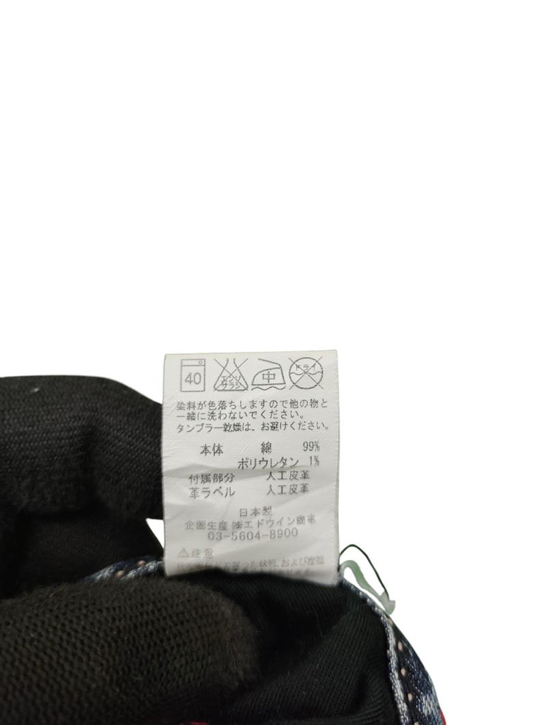 May include: Close-up of a clothing tag with Japanese text and care symbols. The tag lists fabric composition as 99% cotton and 1% polyurethane. Includes washing instructions and the manufacturer's information.