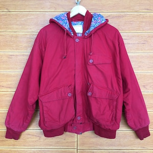 May include: A red hooded jacket with a floral print lining. The jacket has a zipper closure, two flap pockets, and a ribbed hem and cuffs.