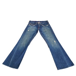 May include: A pair of blue denim jeans with a wide leg opening. The jeans have a distressed look with faded areas and small holes.