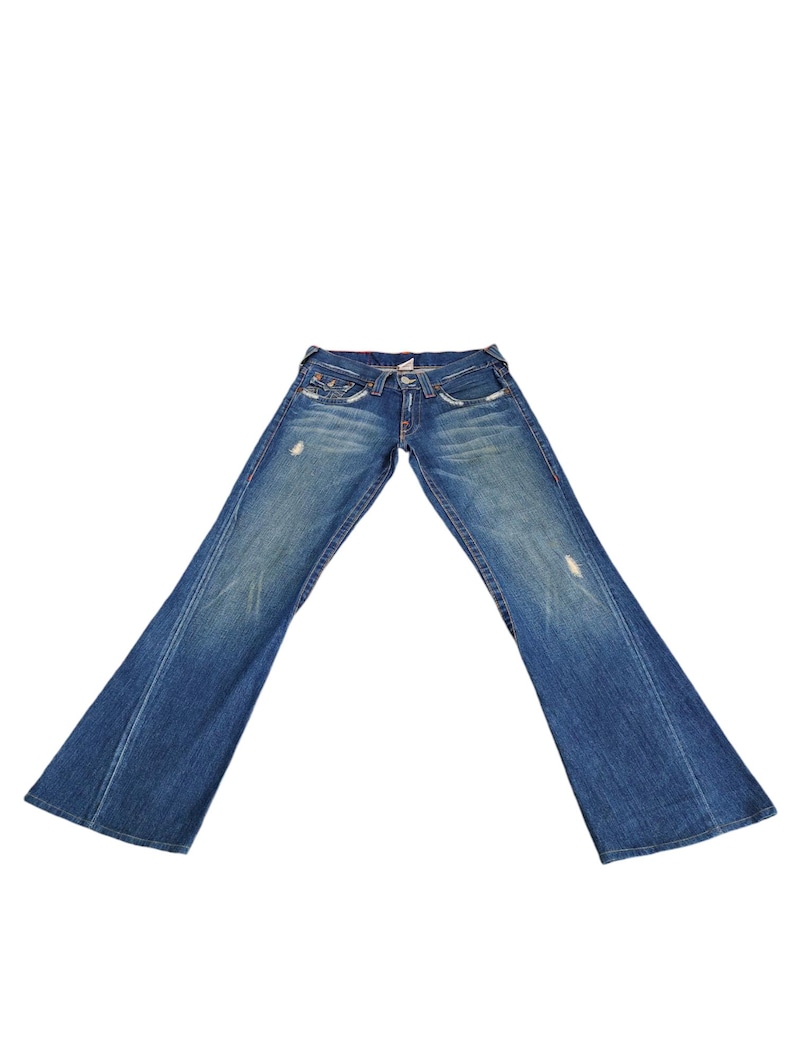 May include: A pair of blue denim jeans with a wide leg opening. The jeans have a distressed look with faded areas and small holes.