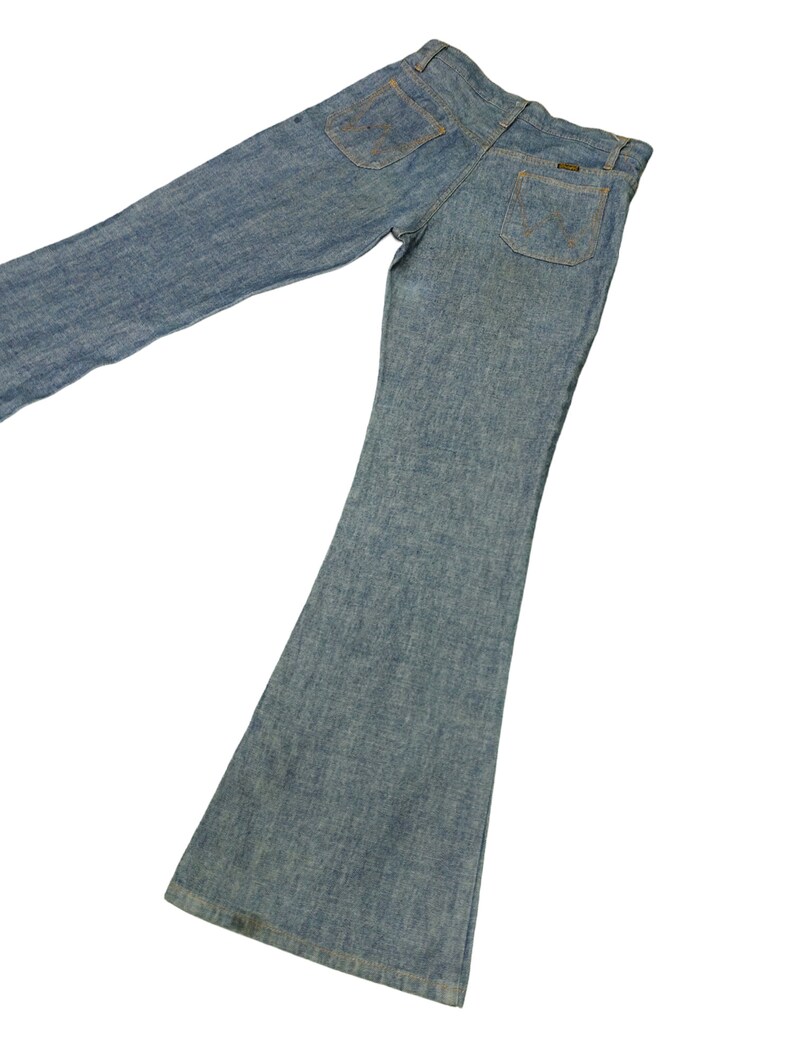 May include: A pair of light blue denim bell bottom jeans. The jeans have a classic five-pocket style with a slightly faded wash.