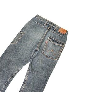 May include: A pair of blue denim jeans with a brown leather patch on the back pocket. The jeans have a faded look and are made of a soft, comfortable material.