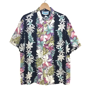 May include: A black short-sleeved button-down shirt with a tropical floral print. The shirt has a collar and a pocket on the left side. The label on the shirt reads "TRU-FOCU".