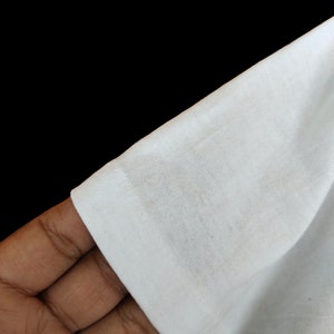May include: Close-up of a white cotton fabric, showing the texture and weave of the material.