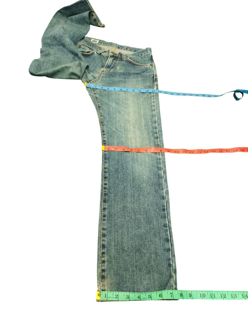May include: Light blue denim jeans with a classic five-pocket design. The jeans are laid flat with measuring tapes across the waist, thigh, and length. The jeans are approximately 30 inches long.