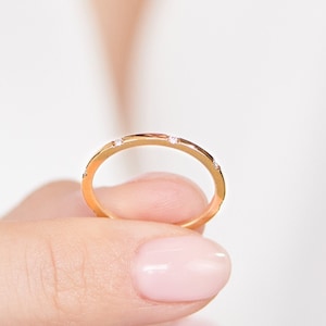 Könnte beinhalten: Ein dünner Goldring mit kleinen Diamanten, die in das Metall gefasst sind.