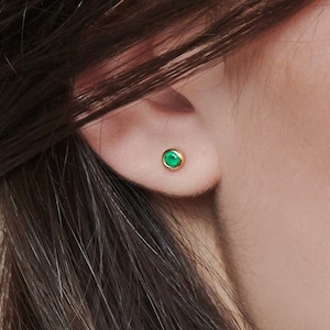 A Beautiful set of yellow gold stud earrings with a tiny round green agate gemstone worn by a model.