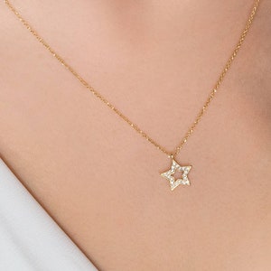 Worn by a model, a yellow gold necklace with a special star outline charm and natural white diamonds embedded in it.