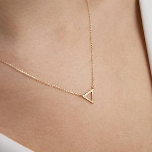 May include: A delicate gold necklace with a simple triangle pendant.