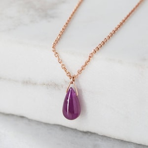 Puede incluir: Un delicado collar de cadena de oro rosa con un colgante de piedra preciosa púrpura en forma de lágrima.