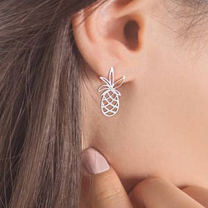 A delicate white gold pineapple stud earring with a white natural diamond in the center of the leaves is shown worn by a model.