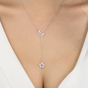 Worn by a model, a special sparkling lariat necklace with two of the most popular outline chams. Both the crescent moon and a star are covered in natural white diamonds in white gold.