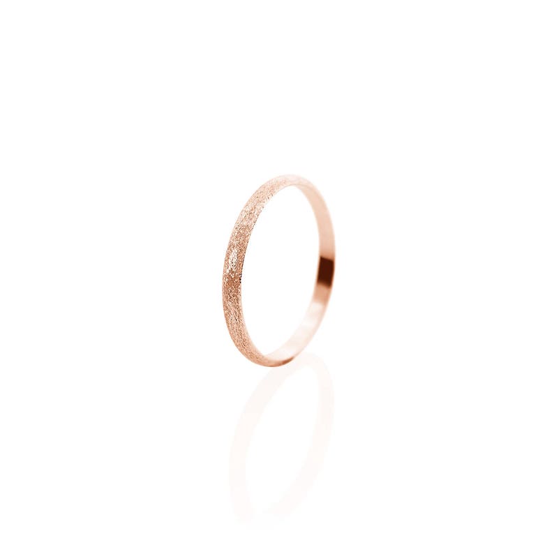May include: A thin rose gold band ring with a textured finish.