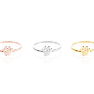 All three color options of the paw print band ring in yellow, white, and rose gold, every option displayed right next to each other on a white background.