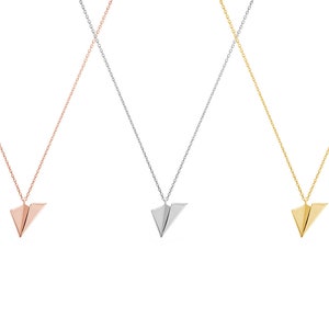 All three color options of the solid gold necklace with a tiny flat paper plane charm attached to it. Rose, white and yellow gold, every option displayed right next to each other on a white background.