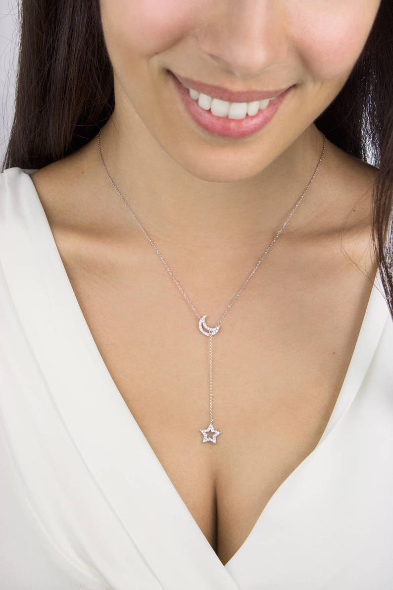 Worn by a model, a special sparkling lariat necklace with two of the most popular outline chams. Both the crescent moon and a star are covered in natural white diamonds in white gold.