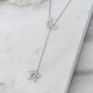 Beautifully shown on a marble display piece, is a special sparkling lariat necklace with two of the most popular outline chams. Both the crescent moon and a star are covered in natural white diamonds in white gold.