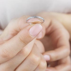 May include: A thin silver band ring with a textured surface.