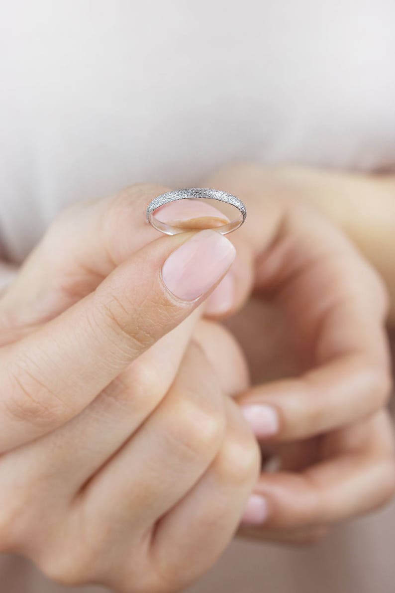 May include: A thin silver band ring with a textured surface.